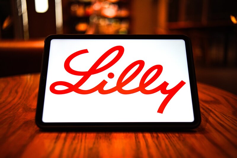 A smart tablet displays a corporate logo with the word Lilly in script lettering.